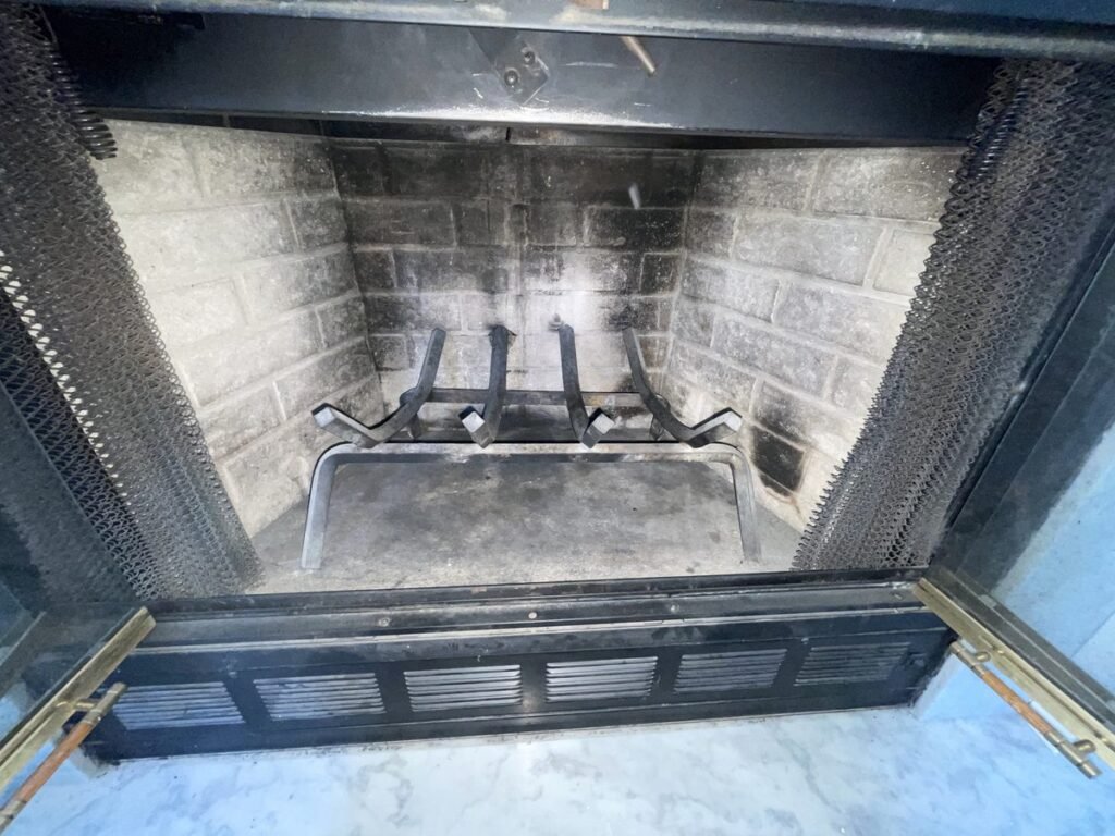 Wood-burning fireplace with the glass doors open during an ABD chimney cleaning visit