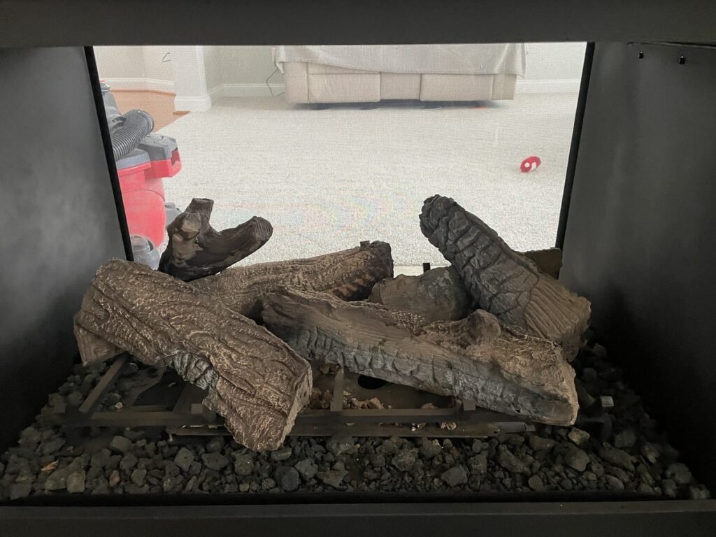Gas log set and lava rock inside a see-through gas fireplace on an ABD service visit